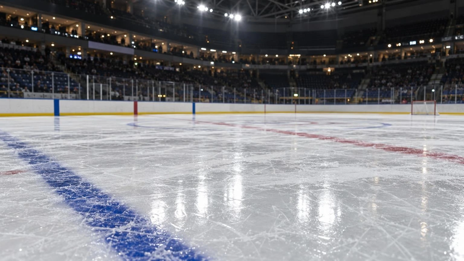 An empty ice hockey rink with red and blue lines under bright arena lights.