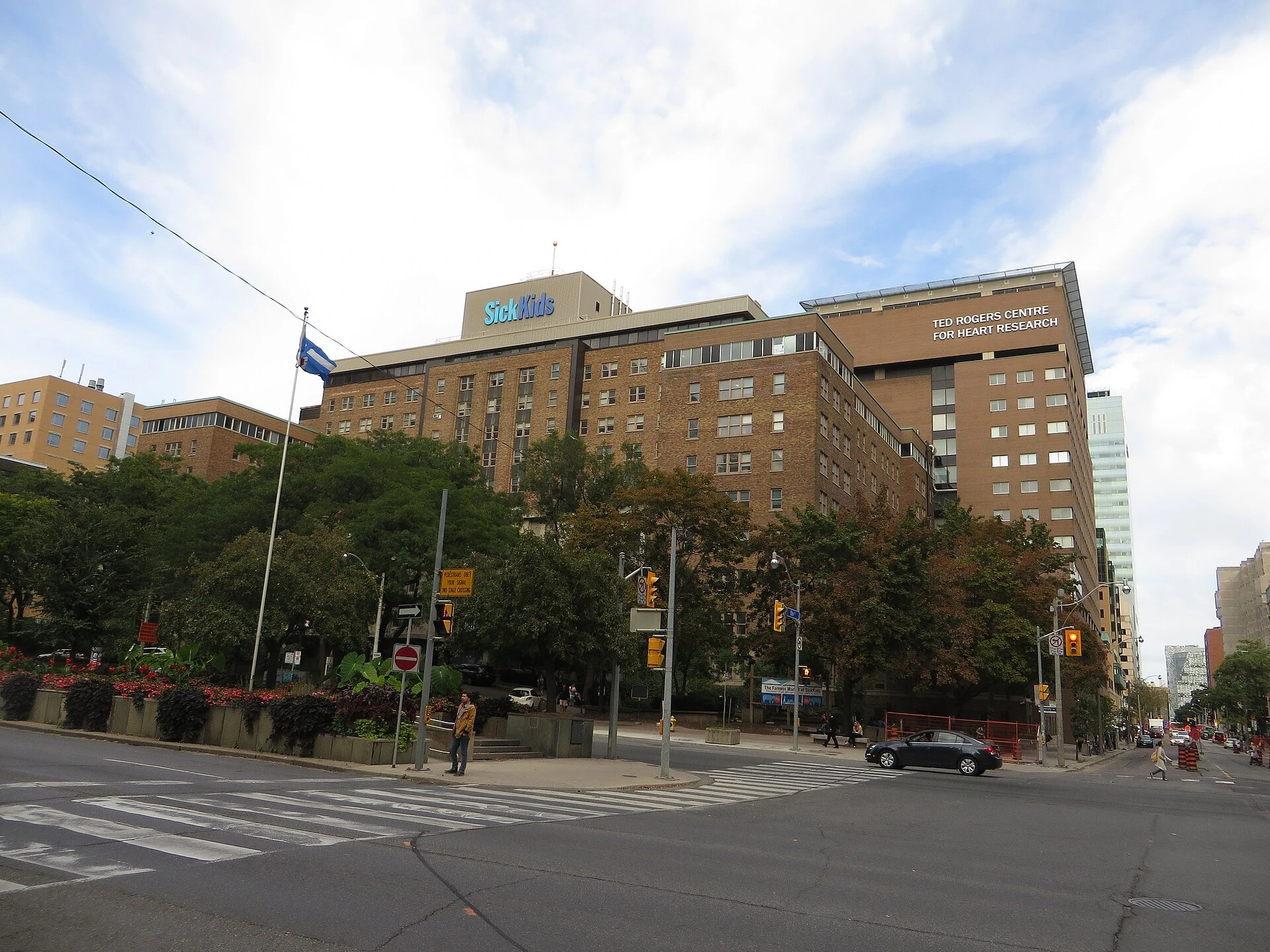 Illustration of a large hospital building on a downtown Toronto street in summer, with visitors walking toward the main entrance.