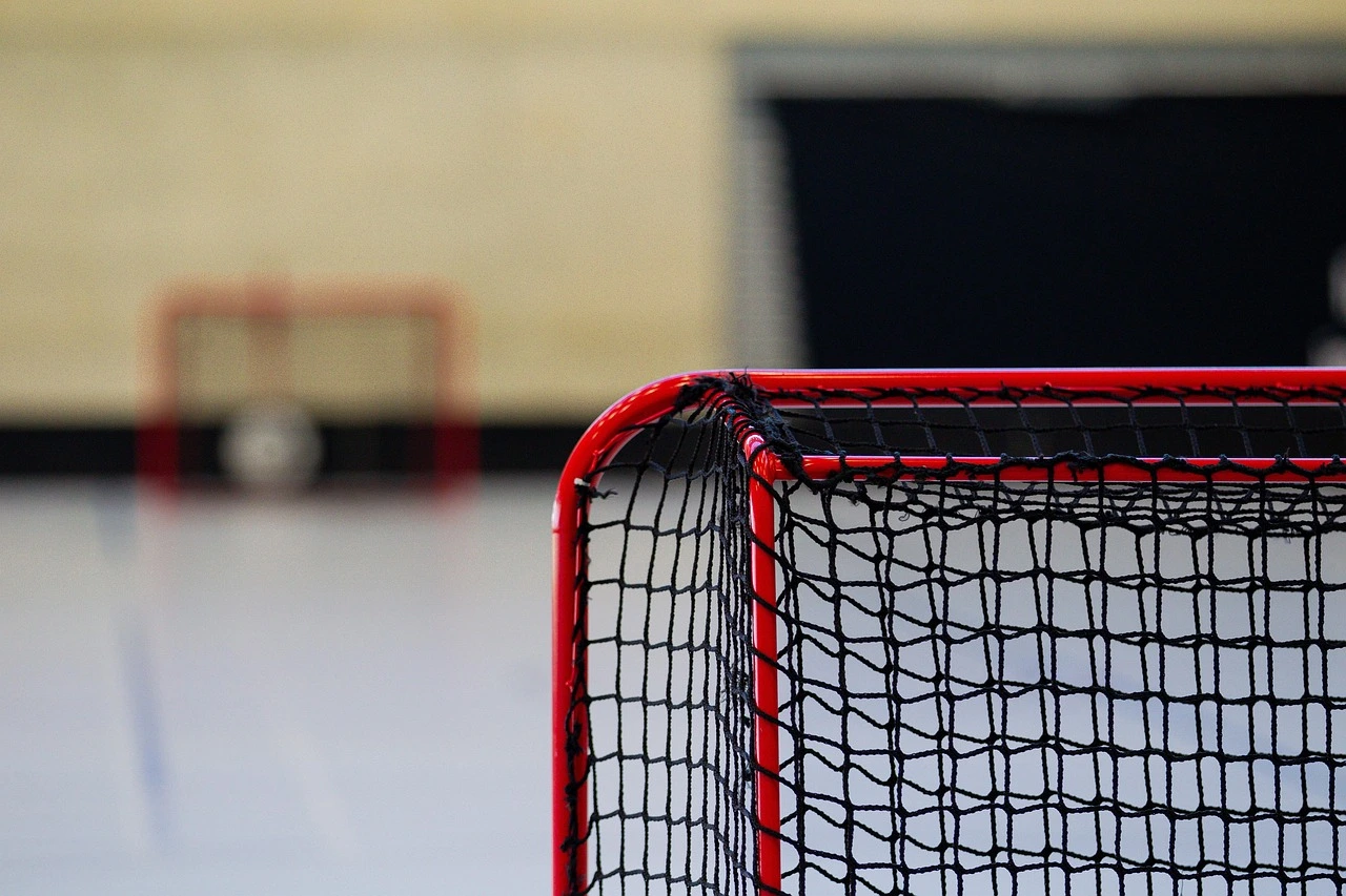 Girls in hockey gear practising drills on a community arena ice surface with coaches.