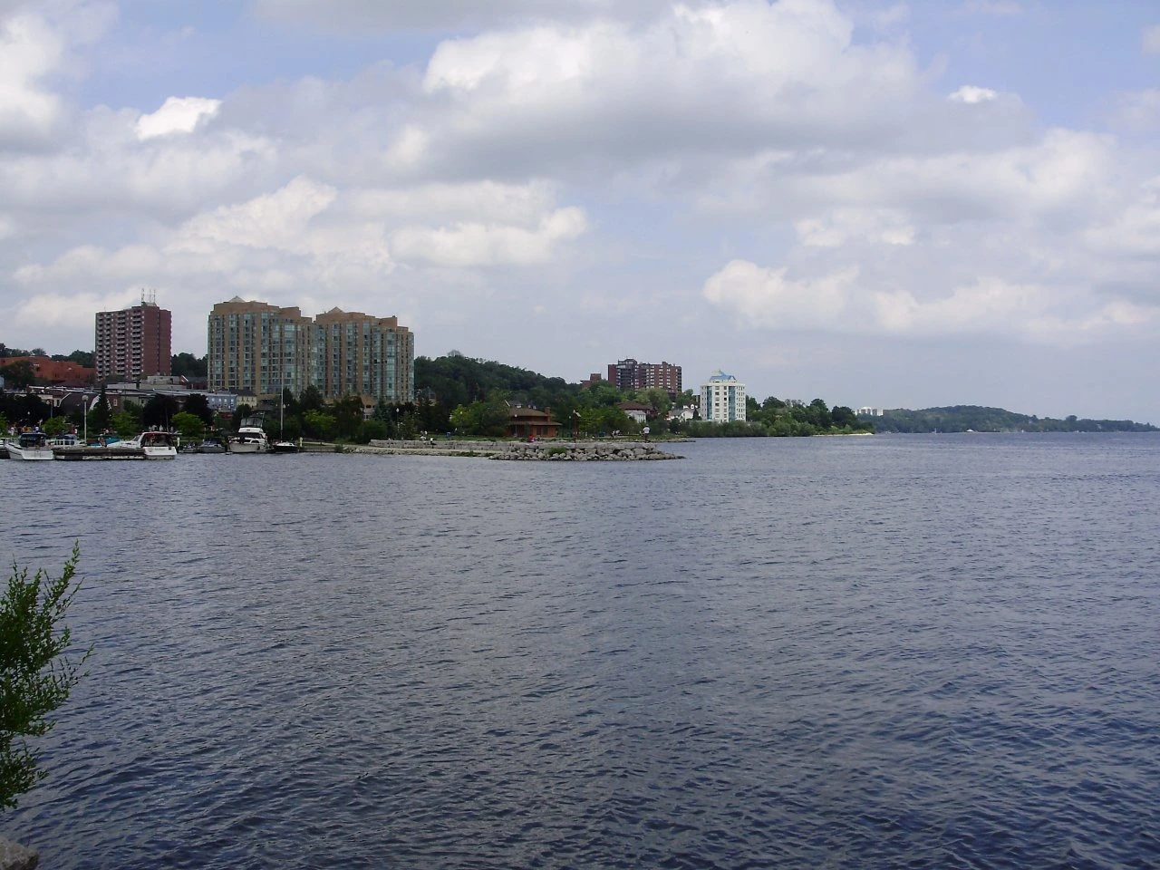A formation of jets trailing white smoke above a waterfront bay lined with parkland and a downtown skyline.