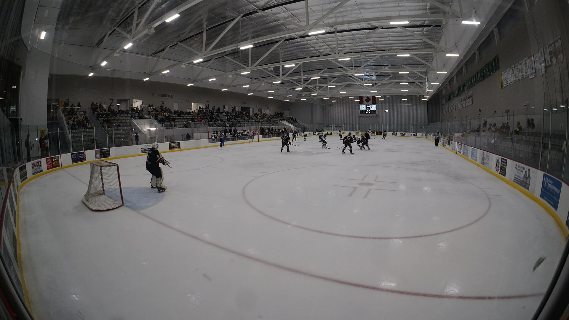 A junior hockey game in a community arena with spectators in the stands.