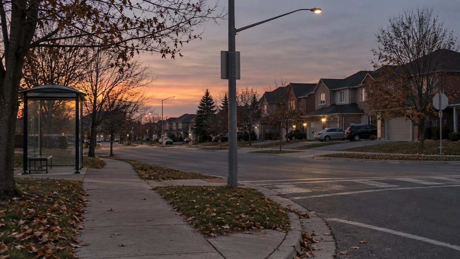 An empty residential sidewalk and a street corner at dusk in an Ontario suburb.
