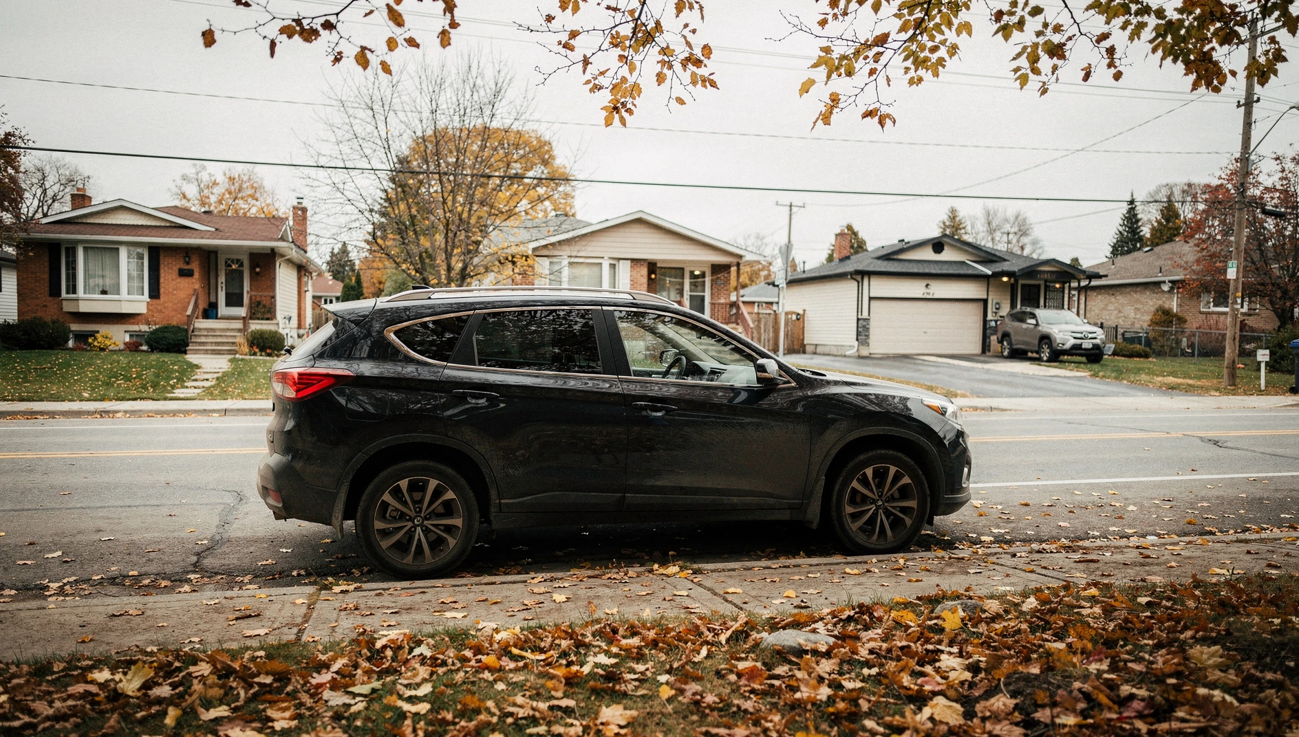 A dark-colored SUV parked on a suburban street in Ottawa during a cloudy autumn afternoon.