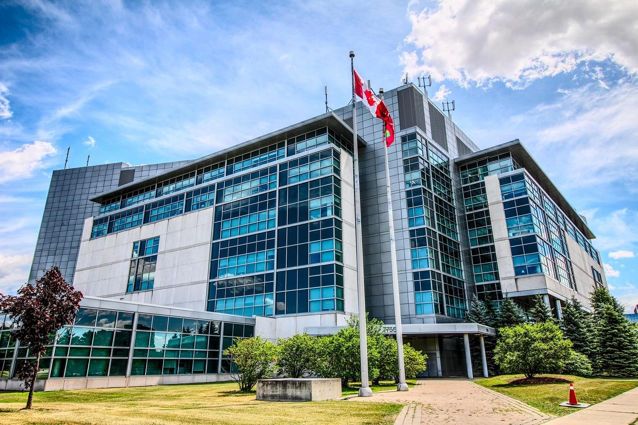 A downtown Ottawa courthouse entrance on a spring day, with pedestrians passing by and Canadian flags above the doors.