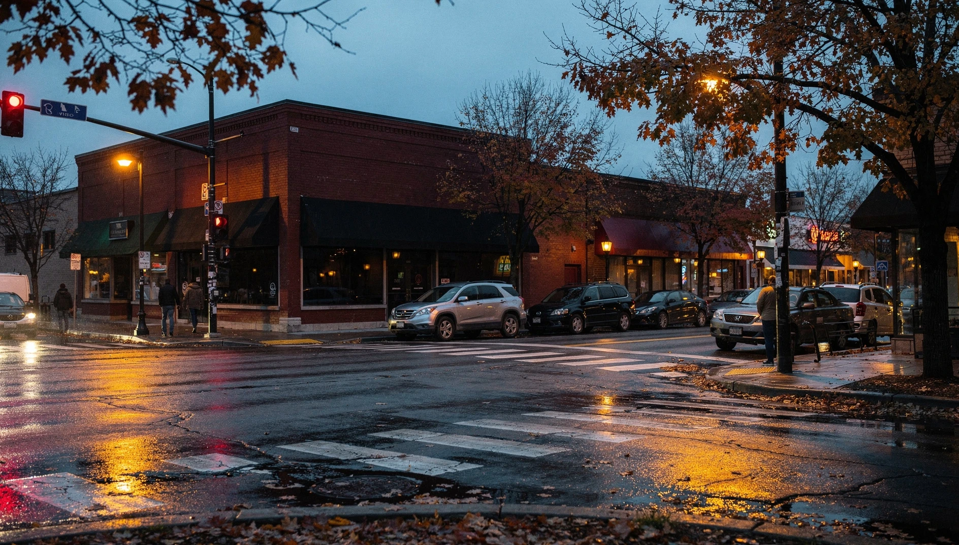 An autumn evening view of a downtown commercial street corner in St. Catharines with wet pavement and lit storefronts.