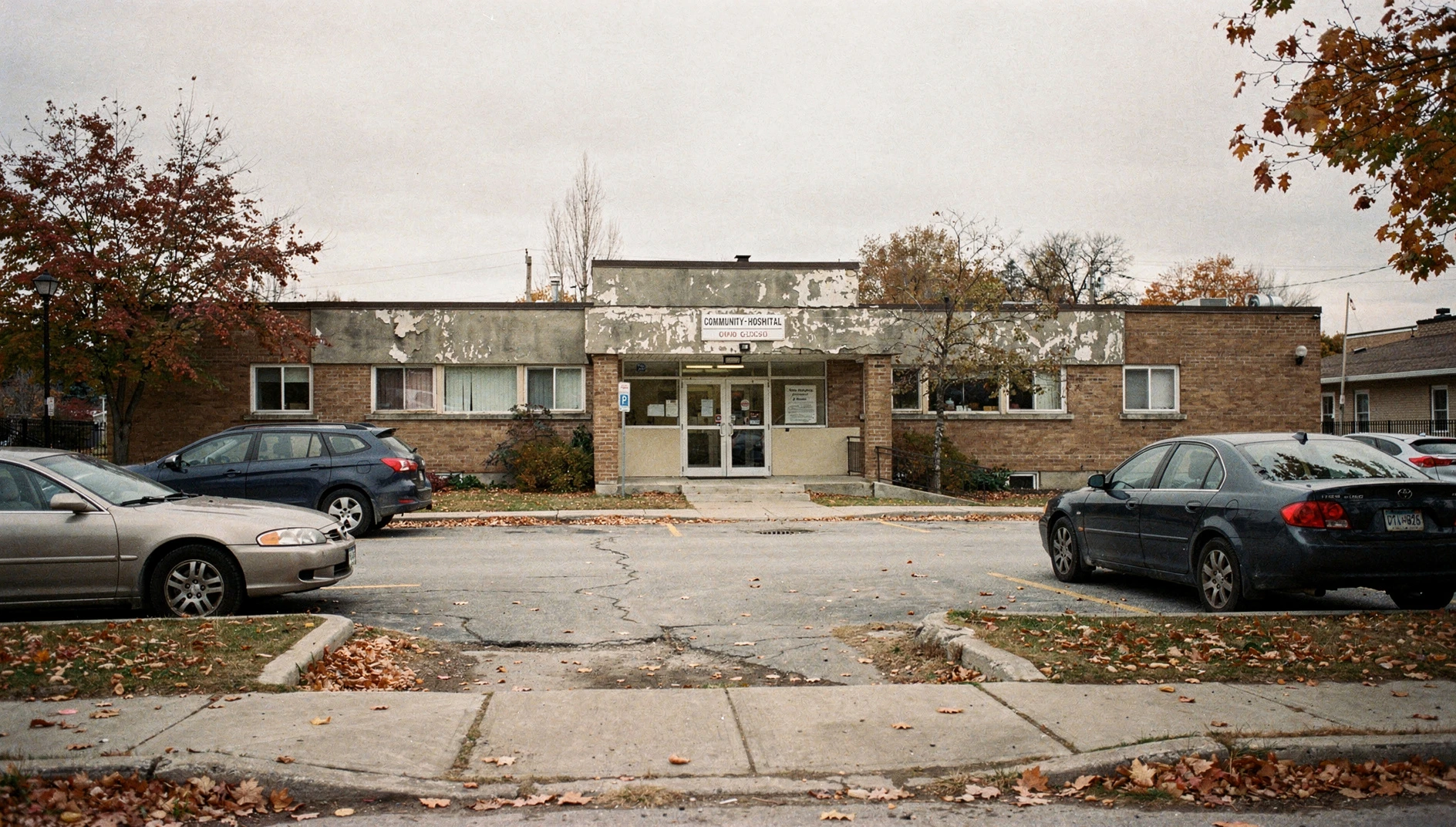 A small-town community hospital building in autumn with parked cars in its lot