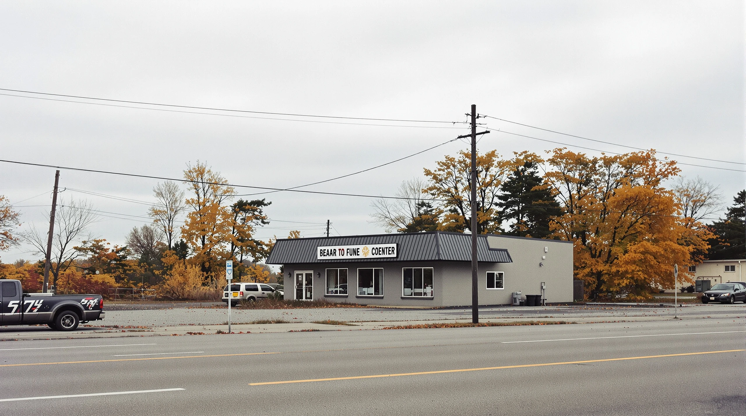 An empty commercial building and overgrown lot surrounded by autumn-coloured trees on a quiet Ontario street.