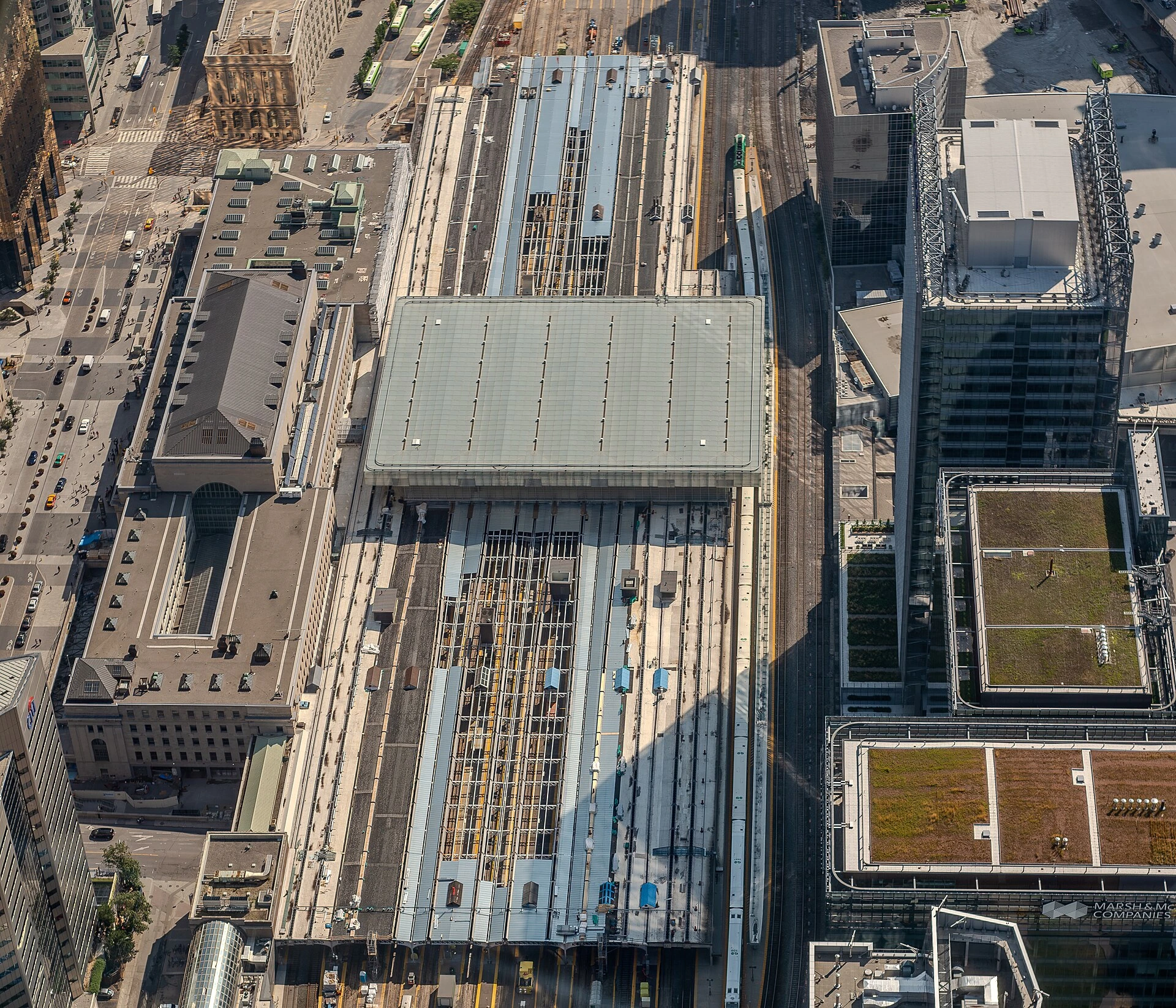 A GO Transit train at a platform under the steel canopy of Toronto's Union Station trainshed, with commuters on the platform.