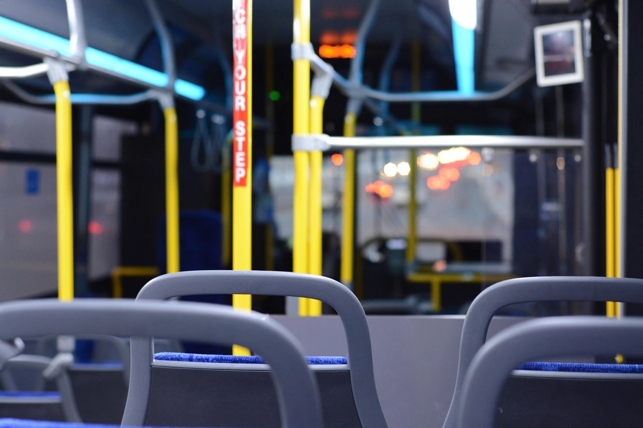 An empty bus shelter at dusk with blurred emergency lights in the background.