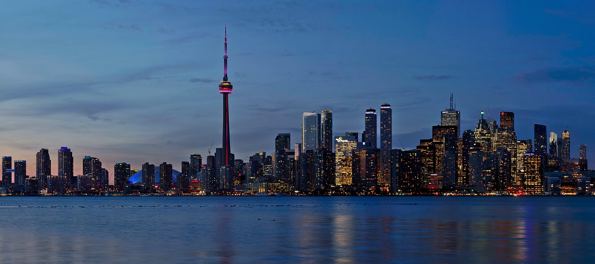 A passenger ferry on the water with the Toronto Islands in the background.