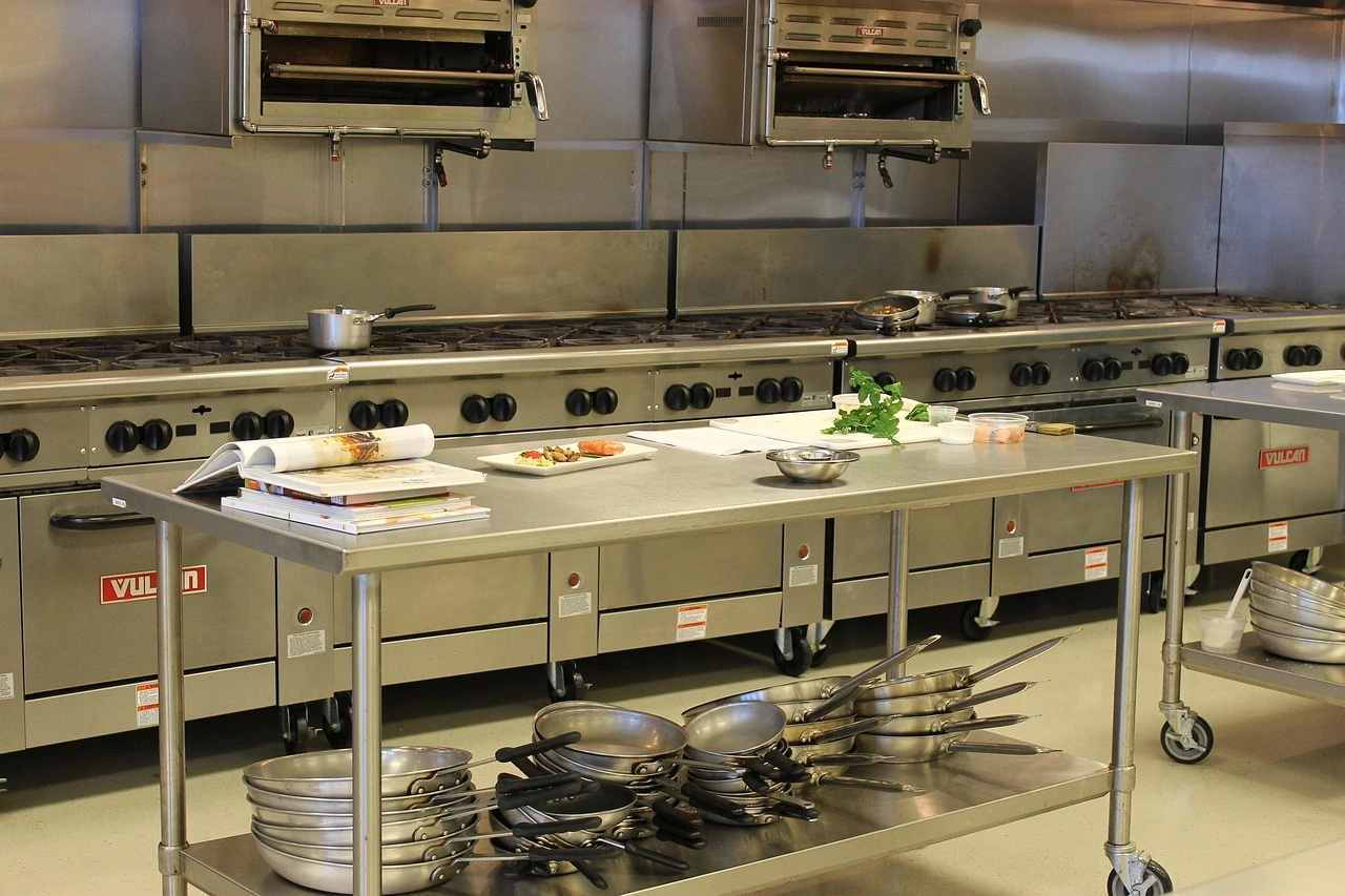 Stainless-steel preparation counters and equipment in a commercial kitchen.