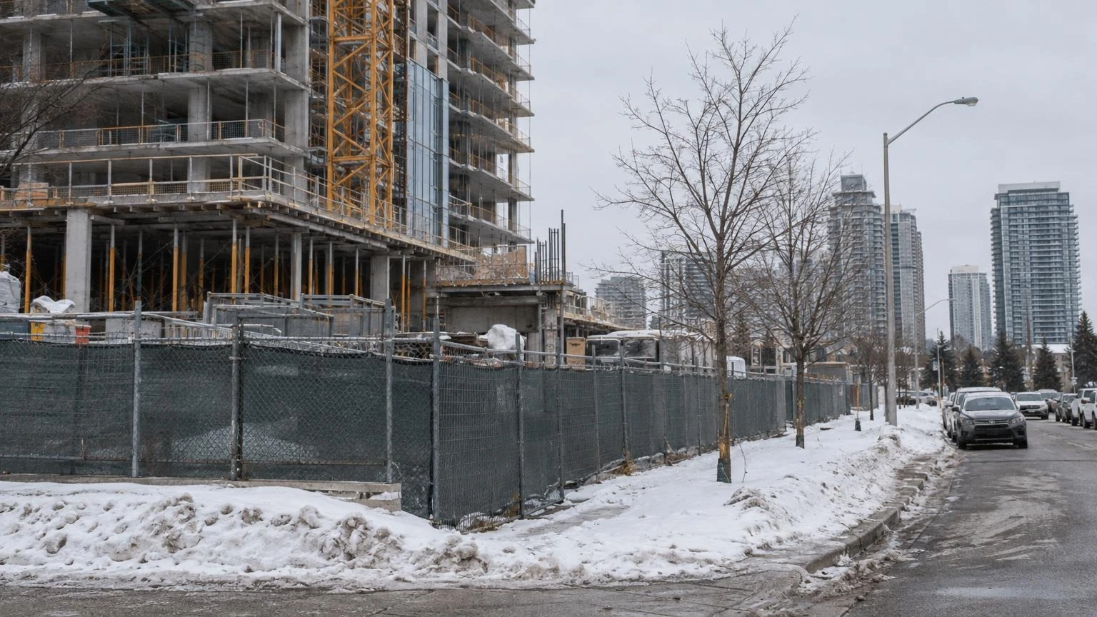 A construction site on a suburban street in Mississauga with a building under development and heavy machinery.