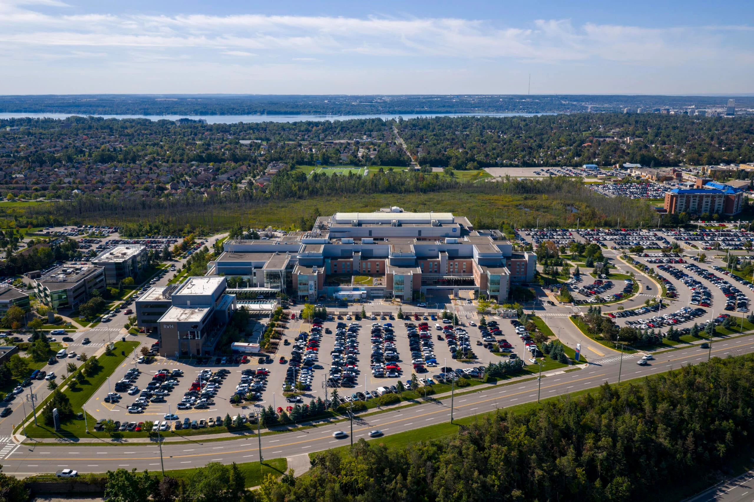 A regional hospital building in autumn with parking areas and staff walking toward the entrance