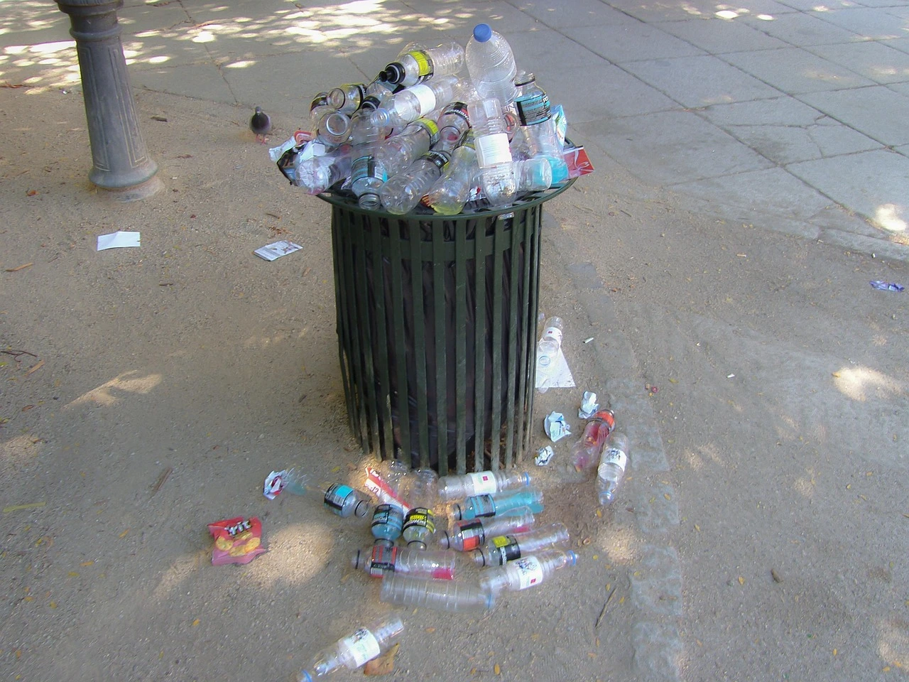 A close-up shot of various reusable items like glass jars and cloth bags sitting on a wooden surface in a bright community setting.