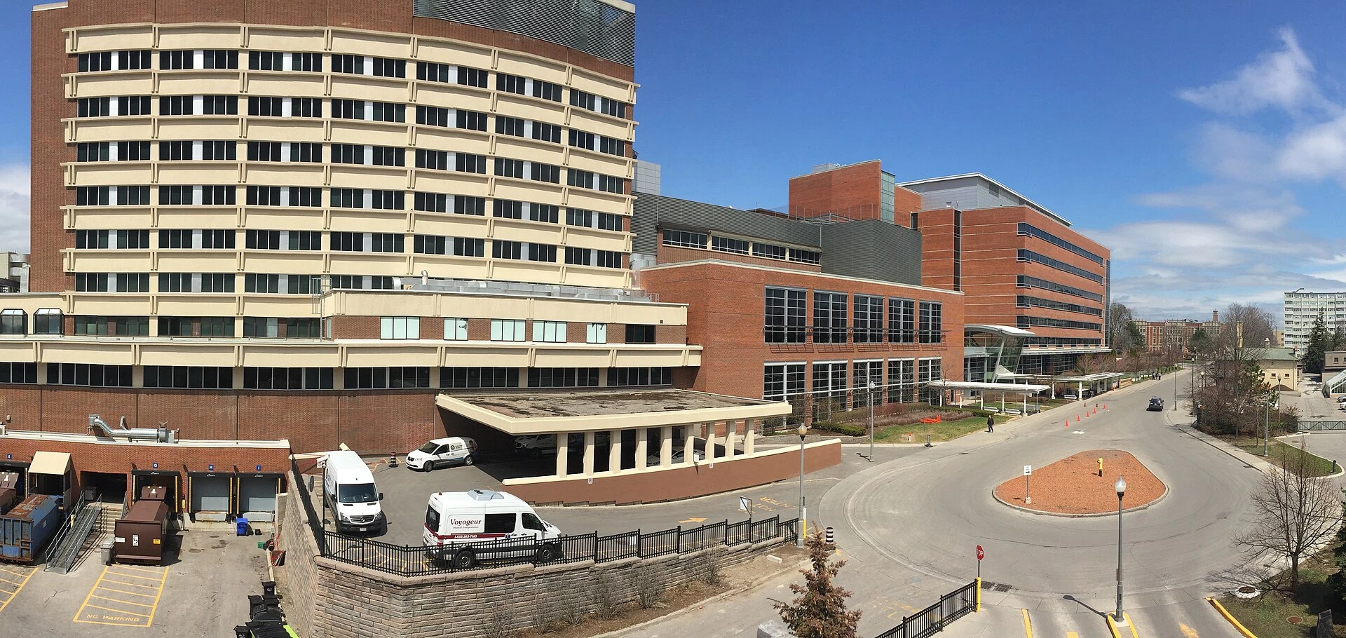 A community hospital building with a main entrance, green landscaping and parked cars on a summer day