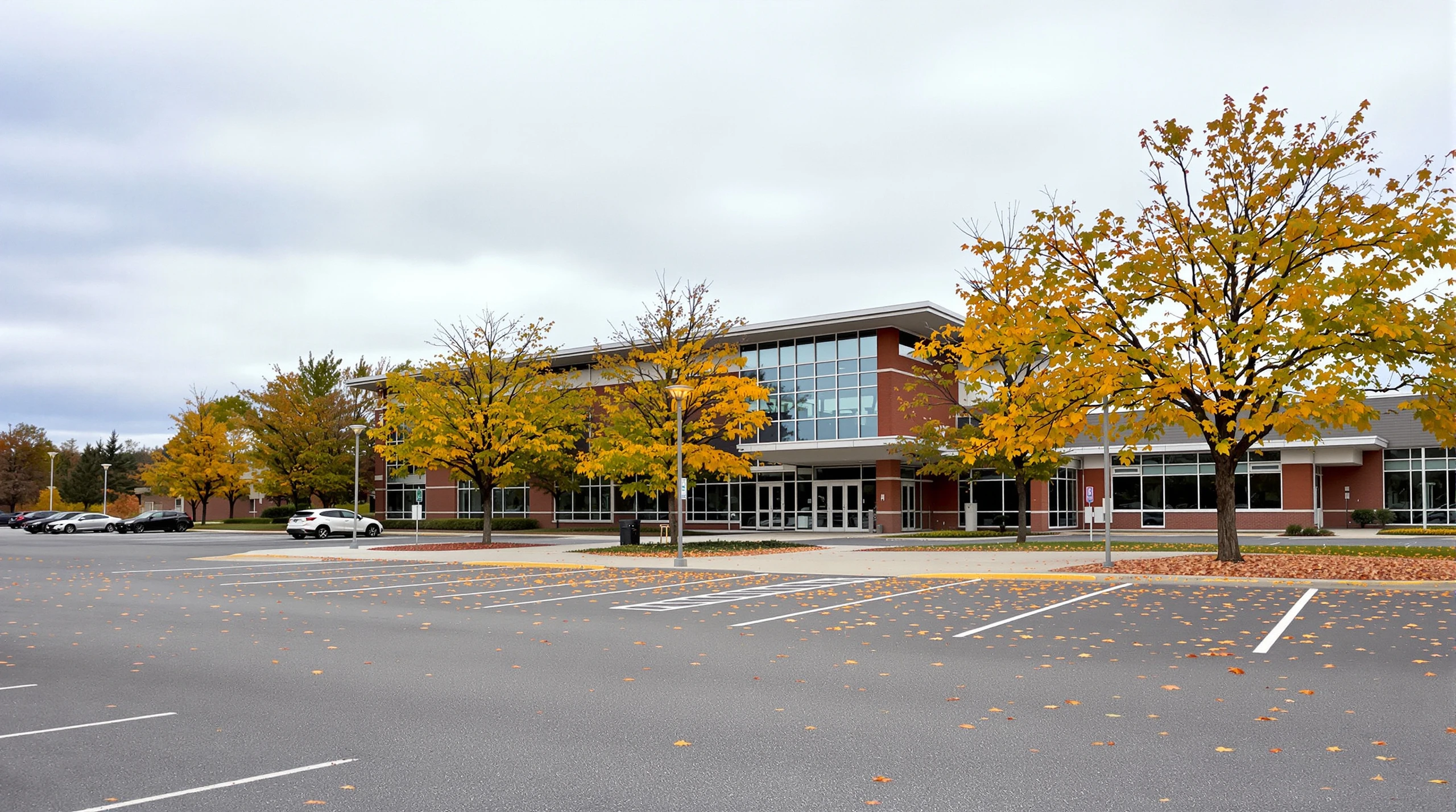 Autumn leaves on the ground outside a municipal sports complex building on an overcast fall day in Whitby.