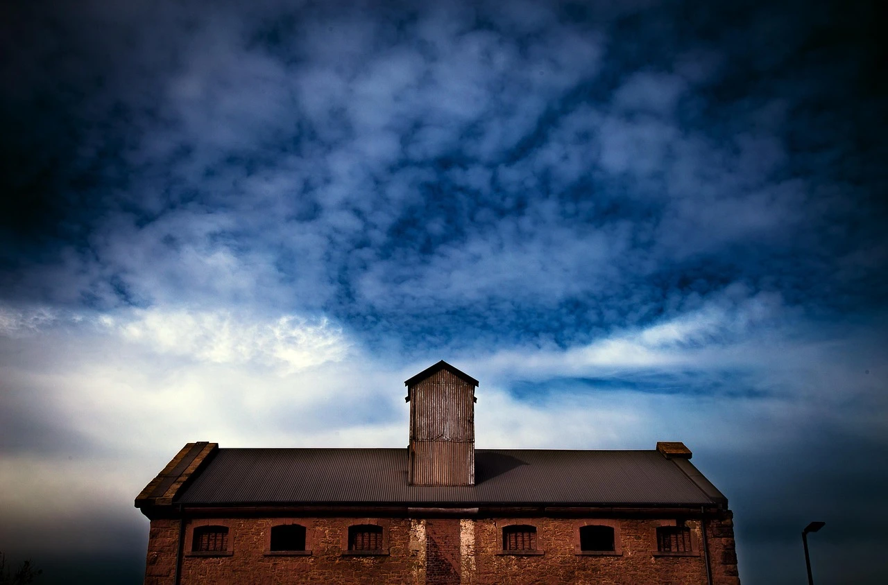 An industrial manufacturing building with loading docks and autumn trees, in autumn light.