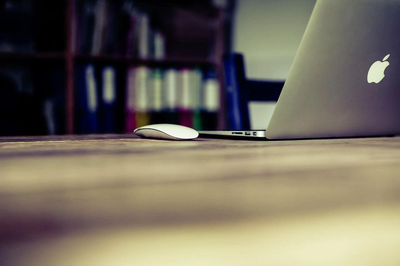 A docked laptop, external monitor and keyboard on an office desk.