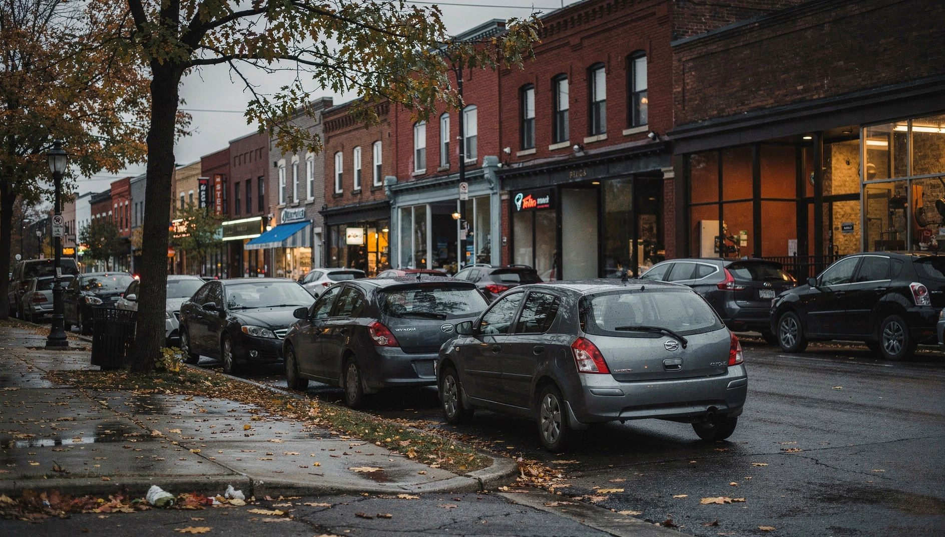 An autumn evening on a downtown St. Catharines street with storefronts and parked cars.