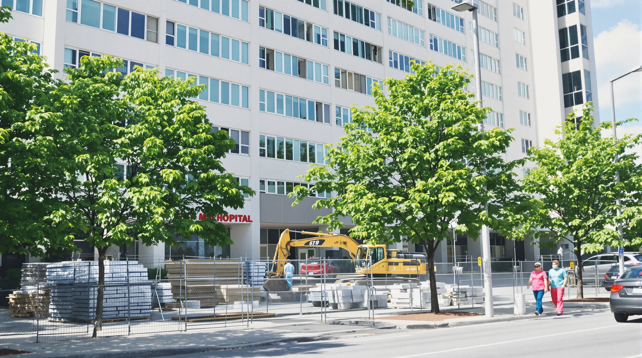 A hospital building in Scarborough with a fenced construction zone and excavator in the adjacent parking area on a summer day.